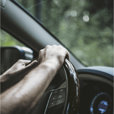 Im Auto mit den Händen am Lenkrad.