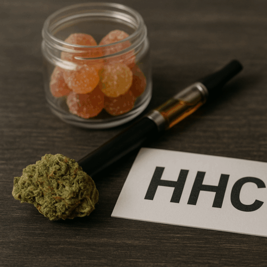 Auf einer dunklen Holzoberfläche liegen verschiedene Produkte mit HHC: eine Cannabisblüte, ein Vape-Pen, Gummibärchen, eine Pipettenflasche und Kapseln. Das Bild visualisiert die Bandbreite von HHC-Produkten, die in Deutschland seit Juni 2024 verboten sind.